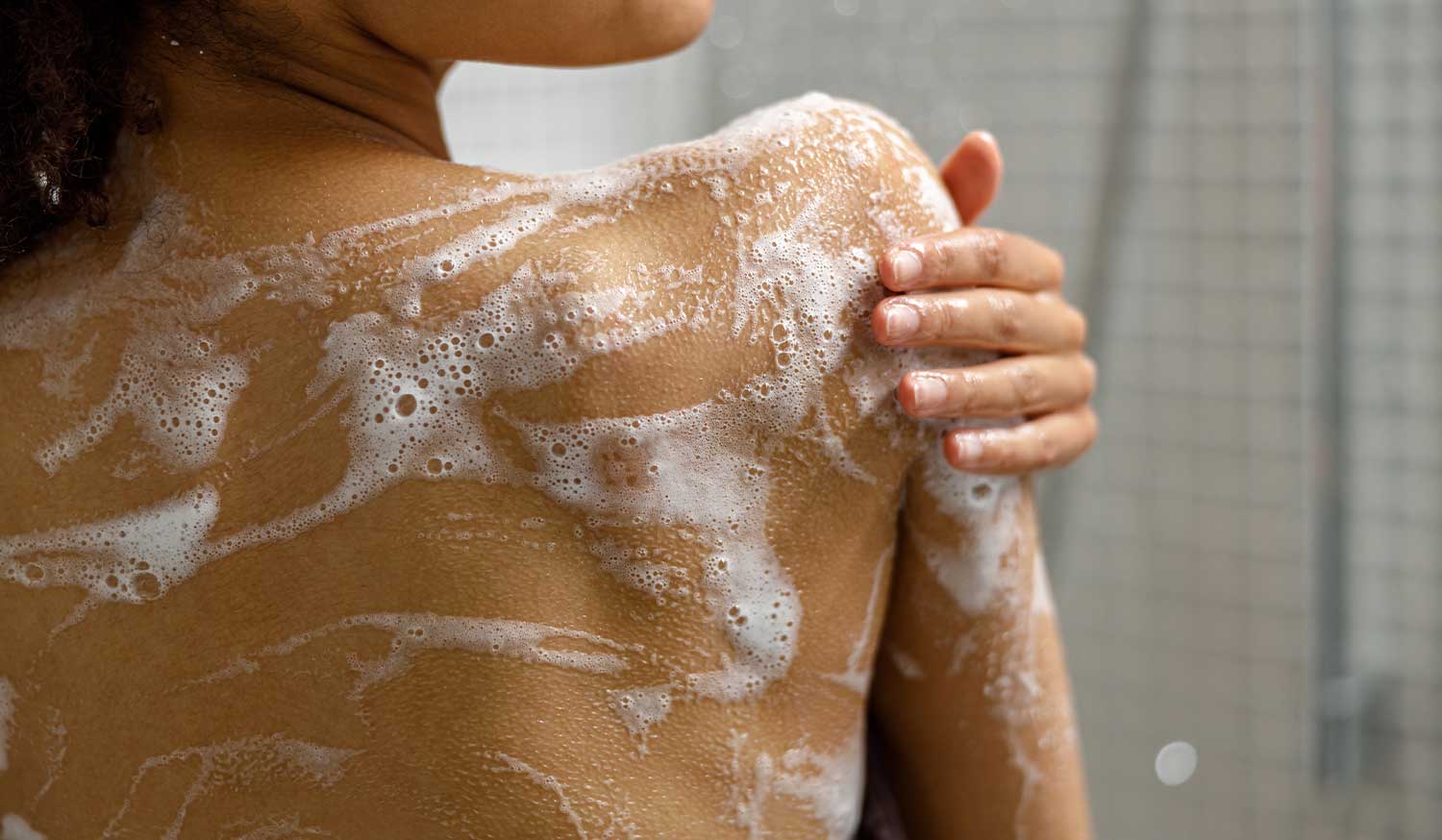 Lathering First Lady Brightening Shower Gel with Niacinamide and Vitamin C over the shoulder and back