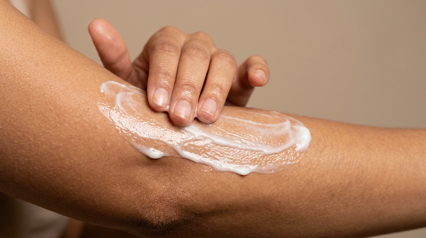 Hand applying Cocoa Butter Body Lotion with Ceramide and Vitamin E to dry skin on arm after showering
